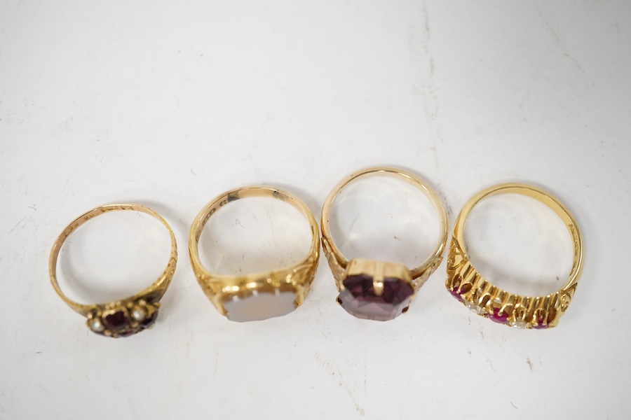 A group of four rings, comprising: a chalcedony signet ring with engraved floral shoulders, size L, partial British hallmarks for 15ct gold; a synthetic ruby and diamond five-stone ring, size N, stamped 18CT; a ring set